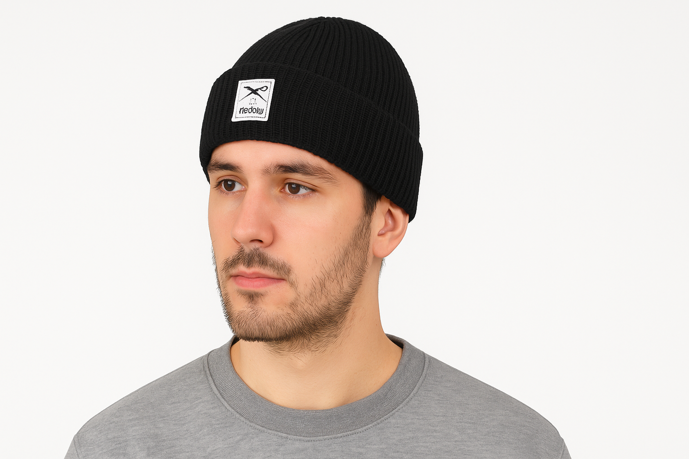 Junger Mann trägt schwarze Iriedaily Mütze mit Label-Logo vor weißem Hintergrund, Seitenansicht.