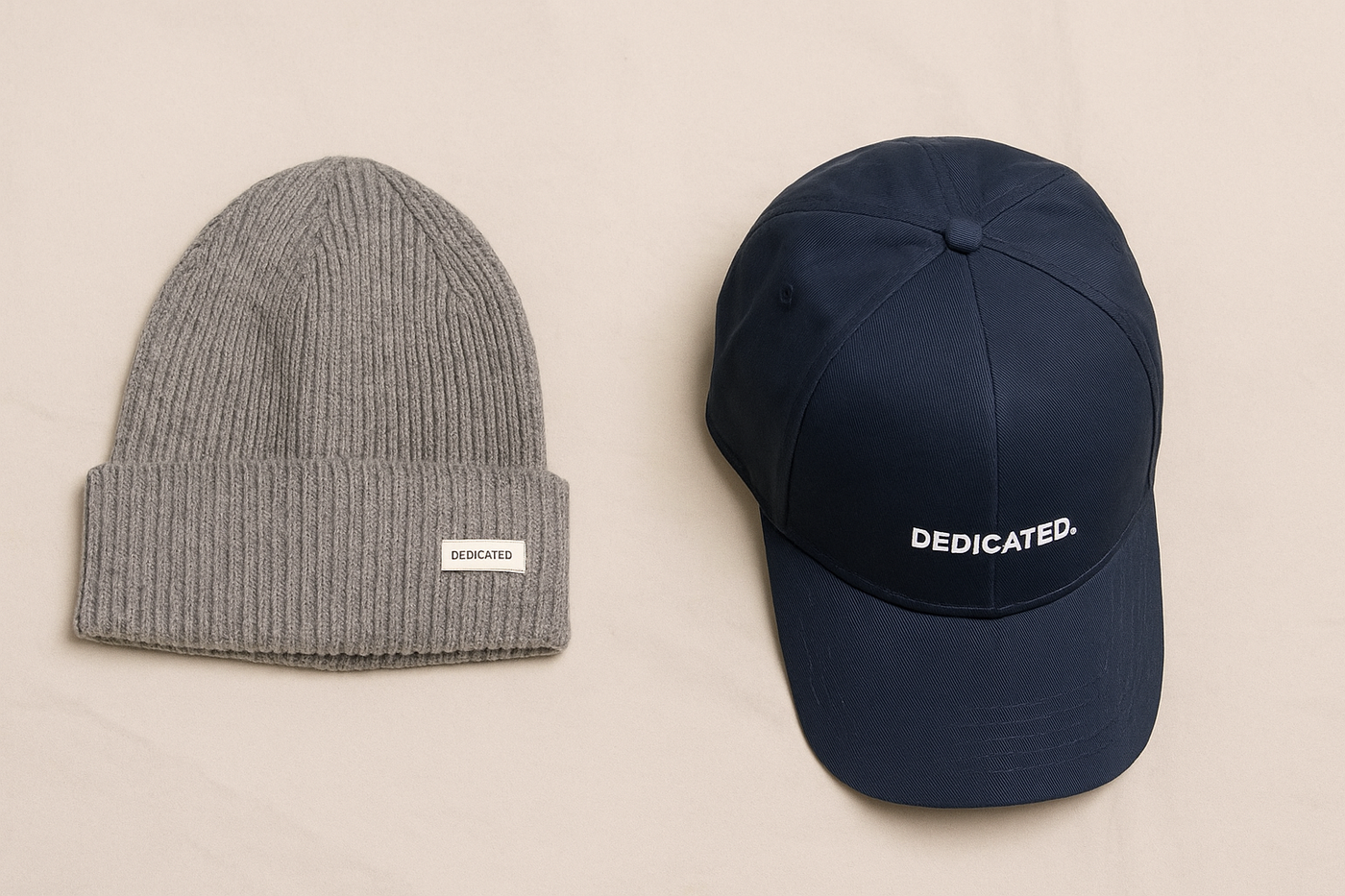 Graue Strickmütze und dunkelblaue Cap von Dedicated auf beigem Hintergrund – minimalistisch und nachhaltig präsentiert.