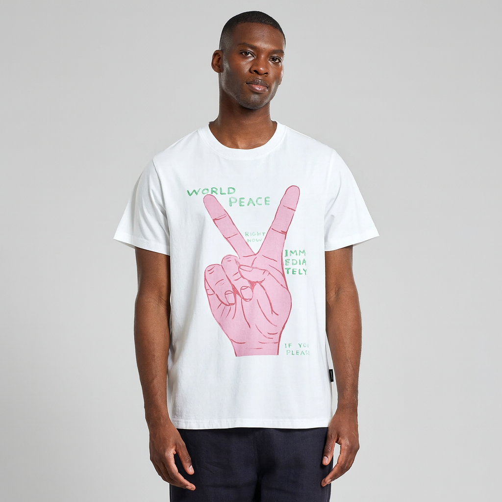 Mann trägt weißes Dedicated T-Shirt mit Peace-Zeichen-Grafik auf grauem Hintergrund.