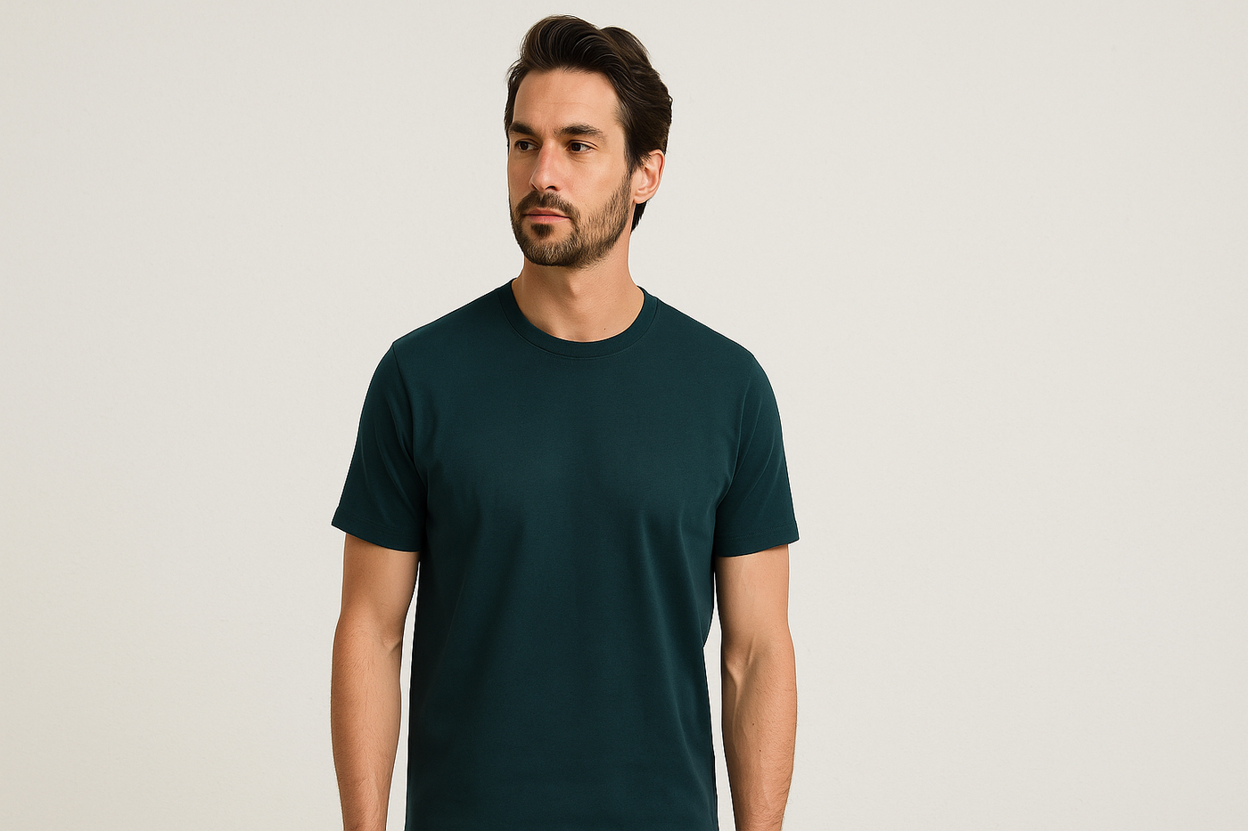 Männliches Model in schlichtem dunkelgrünen T-Shirt aus Bio-Baumwolle vor neutralem Hintergrund.