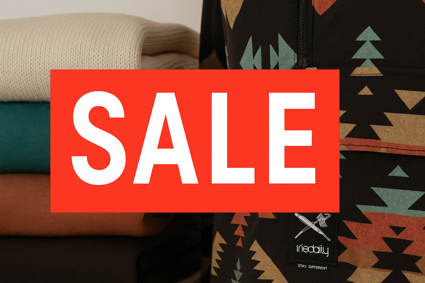 Gestapelte Iriedaily Streetwear in verschiedenen Farben neben einer Jacke mit Tribal-Muster und sichtbarem Iriedaily-Logo – im Vordergrund ein rotes SALE-Schild.