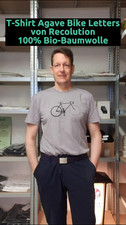 Mann trägt T-Shirt Agave Bike Letters Grey Lilac von Rcolution – nachhaltiges Herren Shirt aus Bio-Baumwolle mit modernem Print und lockerem Schnitt.